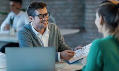Happy businessman talking to his colleague while going through financial reports in the office.