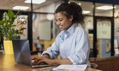side-view-smiley-woman-working-with-laptop-office